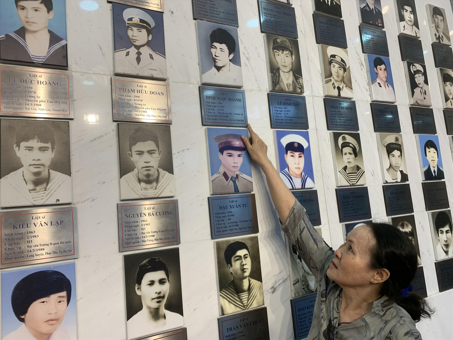 Bà Đỗ Thị Hà bên di ảnh chồng tại Khu tưởng niệm chiến sĩ Gạc Ma. Ảnh: T.M