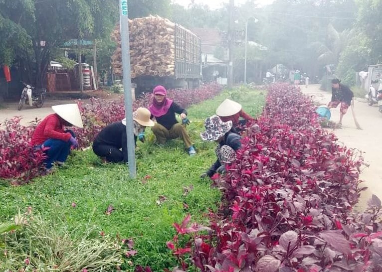 Hội viên phụ nữ chăm sóc đường hoa tại thôn Phương Đông, xã Trà Đông. Ảnh: TRÀ MY