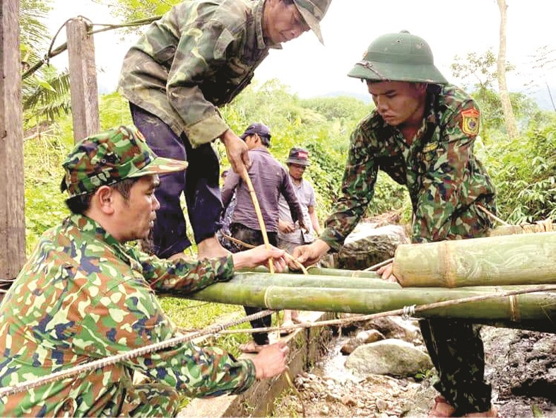 Cán bộ, chiến sĩ Đồn Biên phòng La Êê (Nam Giang) cùng thanh niên địa phương xây dựng cầu tạm giúp người dân vượt lũ.