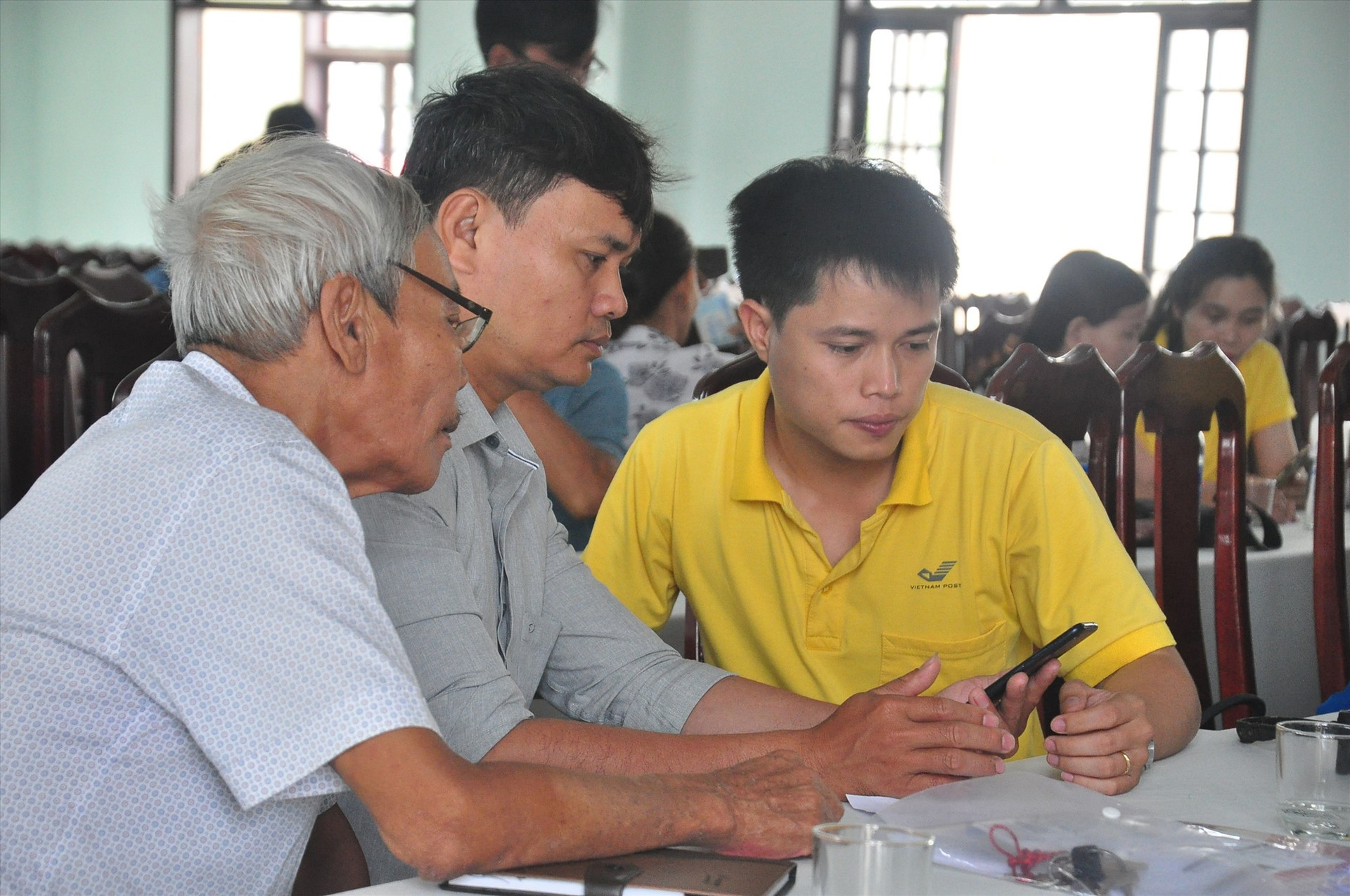 Nhân viên Bưu điện Quảng Nam hướng dẫn cán bộ, người dân cài đặt App Công dân số trên điện thoại thông minh. Ảnh: V.A