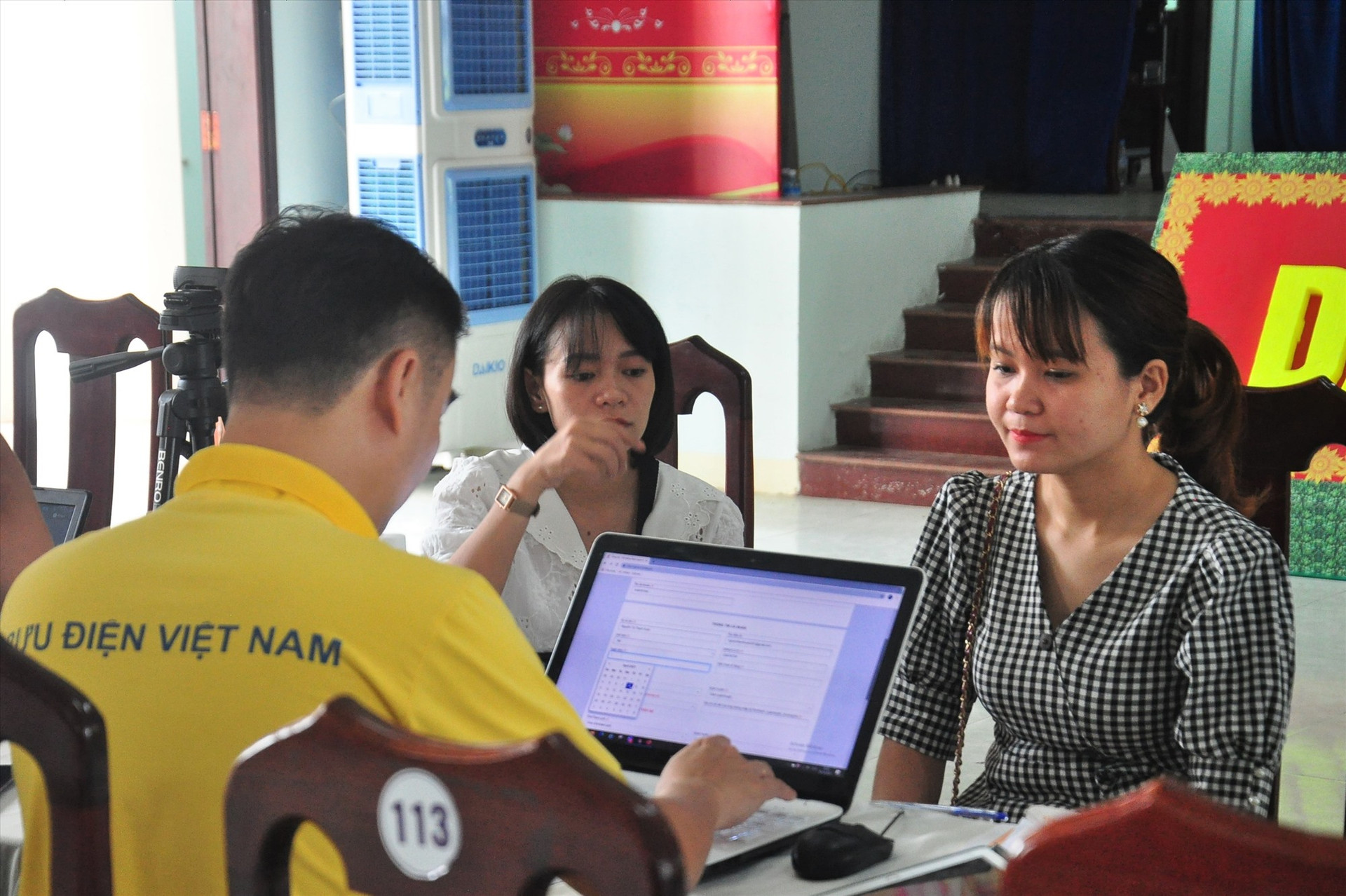Cán bộ, người dân thị trấn Nam Phước được nhân viên bưu điện thực hiện định danh xác thực điện tử miễn phí. Ảnh: VINH ANH