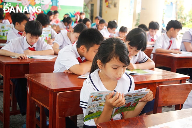 Các em học sinh chăm chú đọc sách trong 