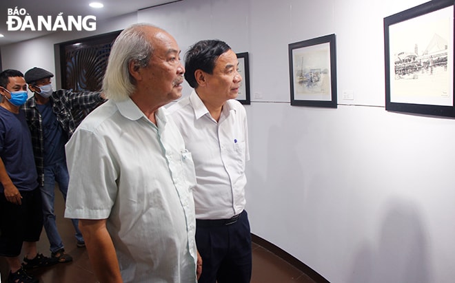 Phó Giám đốc Sở Văn hóa và Thể thao Hà Vỹ (bìa phải) tham quan triển lãm chiều 27-4. Ảnh: XUÂN DŨNG