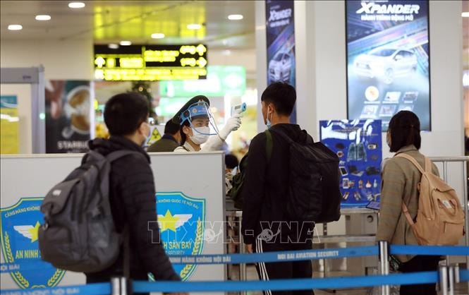 Nhân viên an ninh kiểm tra thân nhiệt của hành khách. Ảnh tư liệu: Huy Hùng/TTXVN
