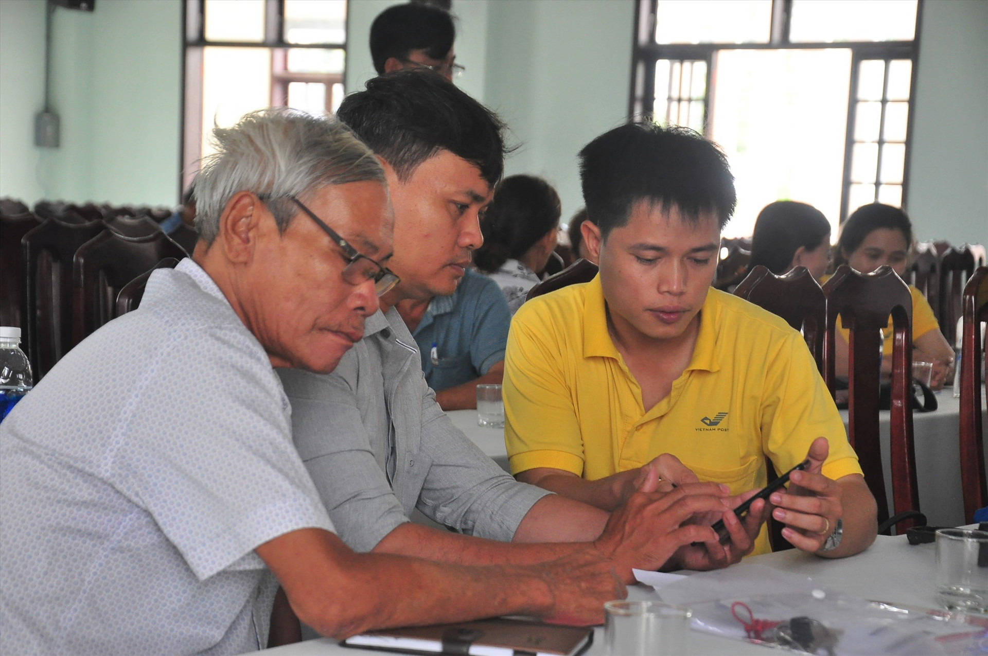 Nhân viên Bưu điện Quảng Nam hỗ trợ người dân cài đặt App công dân số và thực hiện định danh xác thực điện tử. Ảnh: A.H