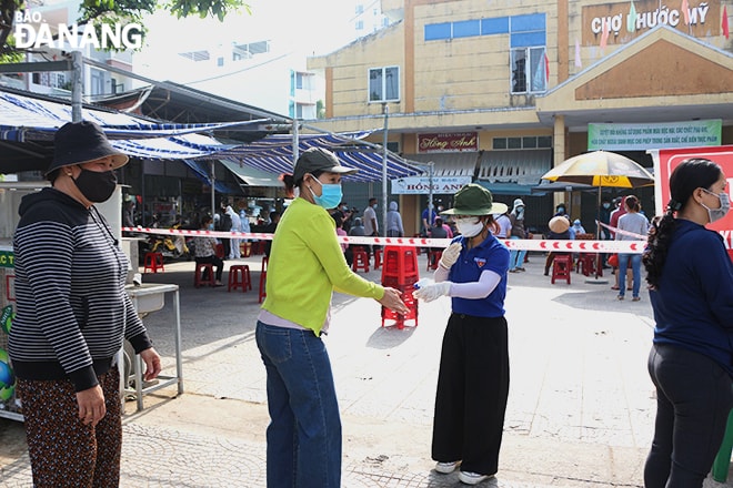 Người dân, tiểu thương đến xét nghiệm được phân luồng, thực hiện sát khuẩn tay. Ảnh: XUÂN DŨNG
