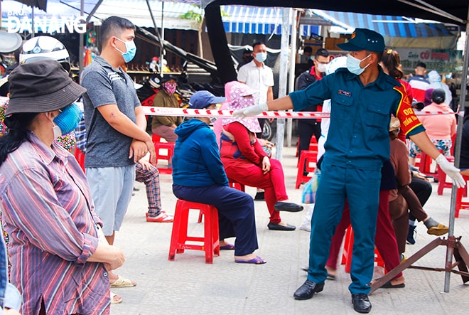Các lực lượng chức năng bảo đảm an ninh trật tự, khoảng cách và hướng dẫn tiểu thương, người dân vào lấy mẫu xét nghiệm. Ảnh: XUÂN DŨNG