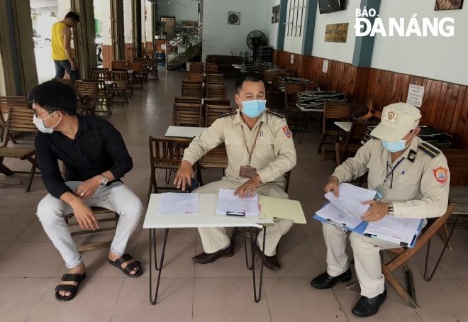 Lực lượng chức năng quận Thanh Khê yêu cầu các chủ cửa hàng, quán ăn, kí cam kết thực hiện nghiêm các biện pháp phòng, chống dịch. Ảnh: VĂN HOÀNG.