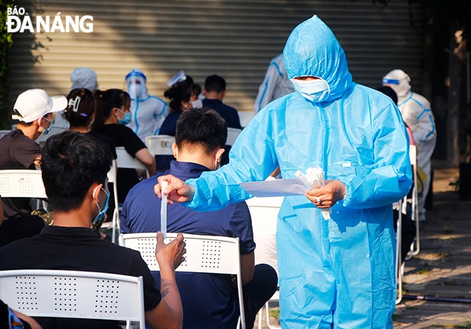 Nhân viên y tế phát mẫu xét nghiệm cho công nhân, người lao động trong Khu Công nghiệp An Đồn. Ảnh: XUÂN DŨNG
