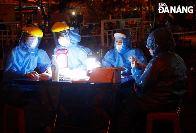Làm việc xuyên đêm dưới ánh đèn. Ảnh: XUÂN DŨNG
