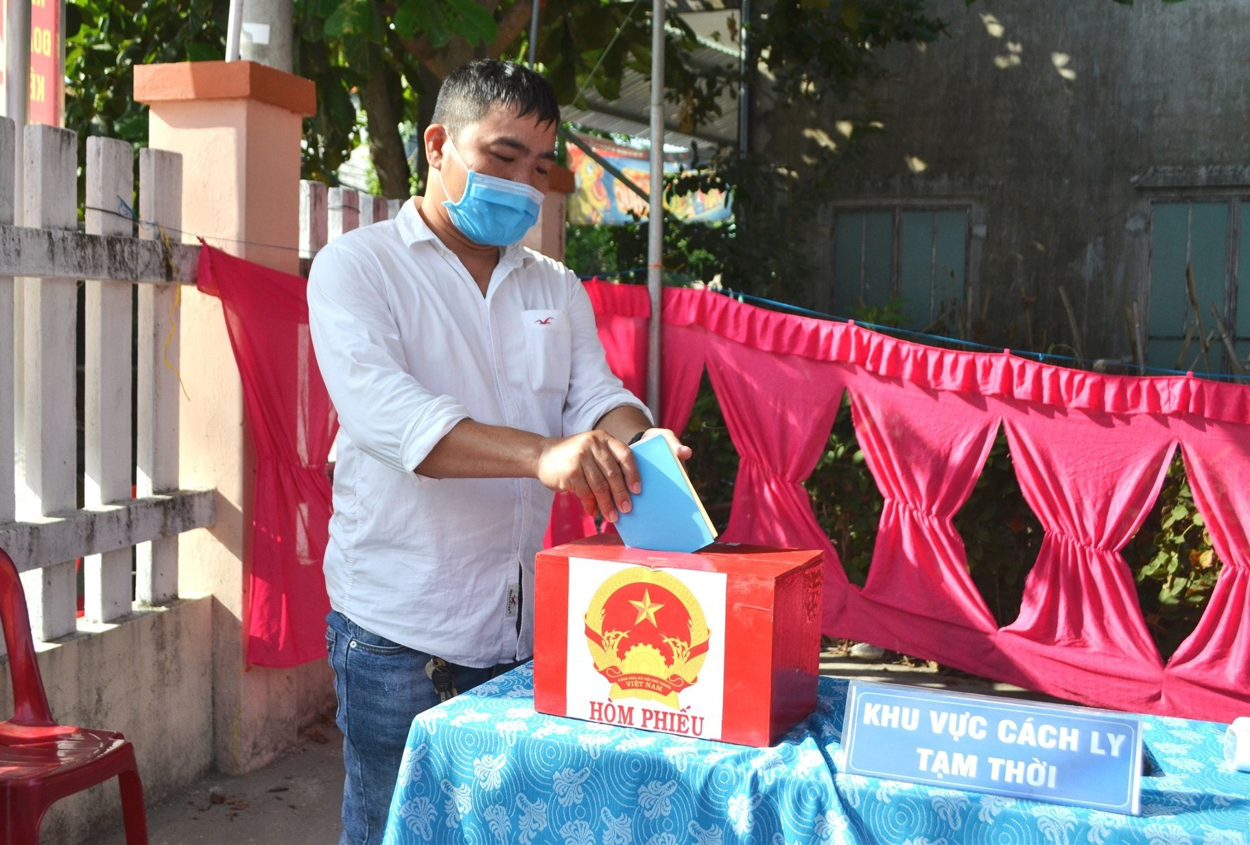 Cử tri bị sốt thực hiện quyền bầu cử trước khi được đưa đến Trạm Y tế phường Vĩnh Điện. Ảnh: TÚ-ĐOAN