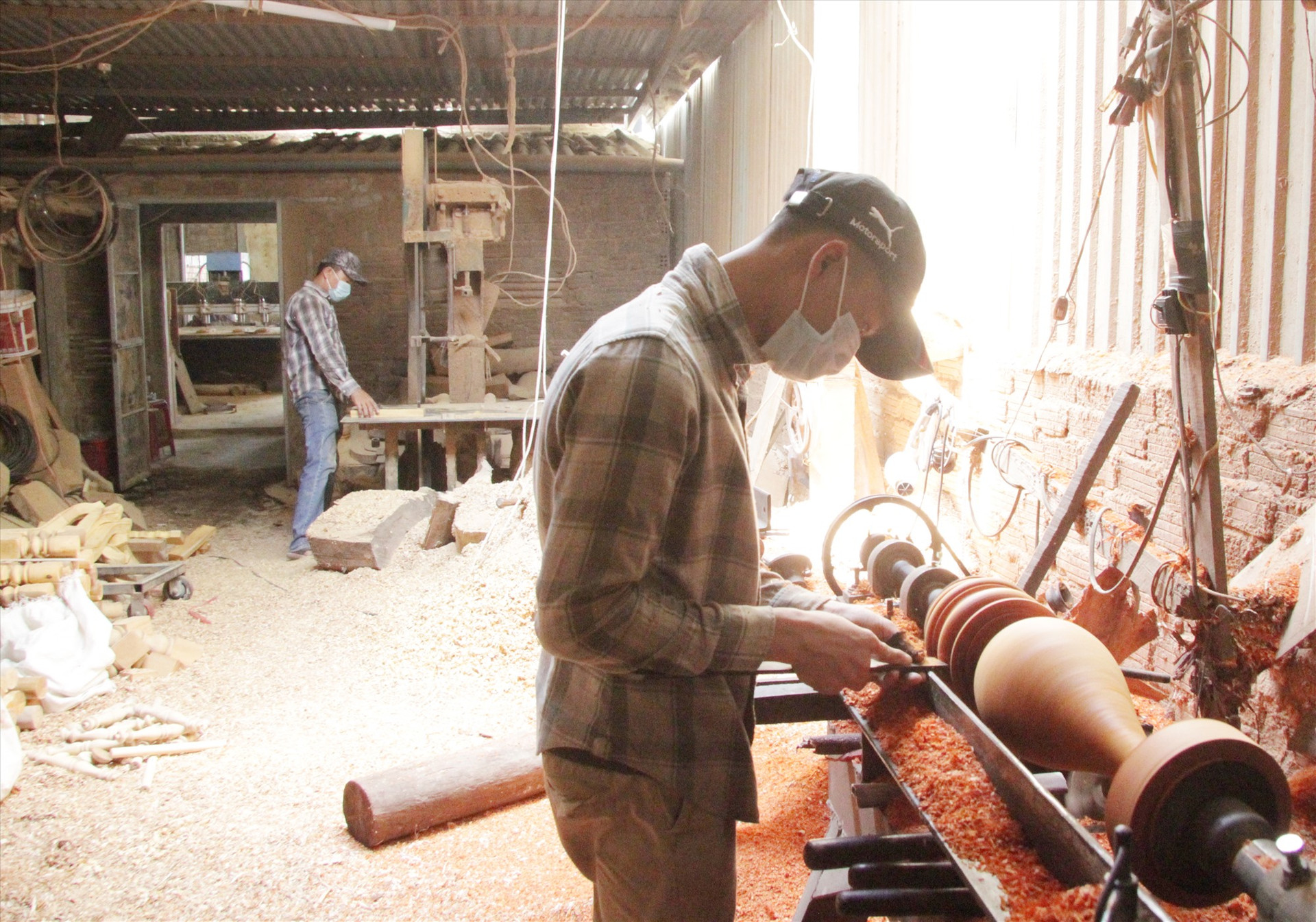 Người thợ tại Tiện gỗ CNC Thành Công đang chế tác hình thụ một chiếc lục bình gỗ bằng máy móc hiện đại. Ảnh: H.Q