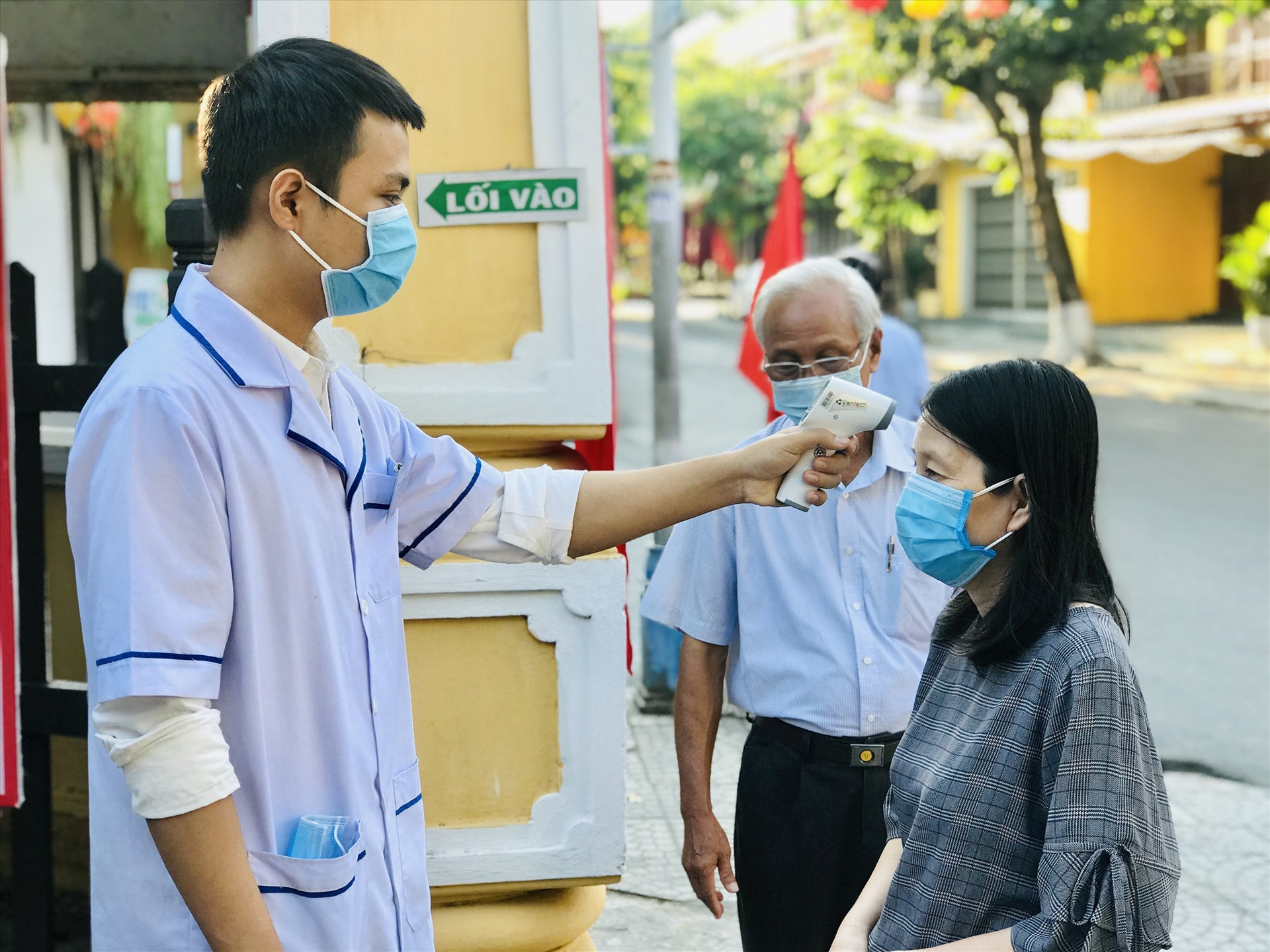 Lực lượng y tế đo thân nhiệt cho cử tri tại phường Cẩm Phô.