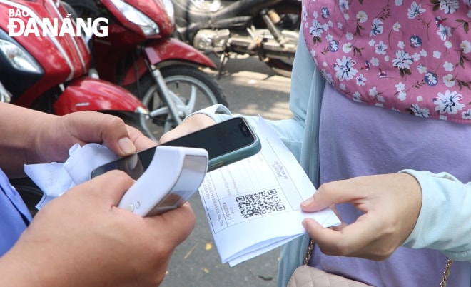 Khi vào chợ, người dân chỉ cần đưa thẻ vé có mã QR Code để nhân viên BQL chợ quét mã. Ảnh: VĂN HOÀNG