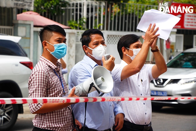 Phó Chủ tịch UBND quận Sơn Trà Huỳnh Văn Hùng (giữa) đọc quyết định dừng thiết lập cách ly y tế đối với chung cư 12T3. Ảnh: XUÂN DŨNG