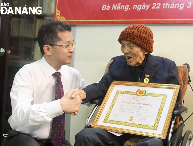 Bí thư Thành ủy Nguyễn Văn Quảng (bên trái) trao Huy hiệu 80 năm tuổi Đảng cho đồng chí Trần Thận, ngày 22.3.2021. Ảnh: ĐẶNG NỞ