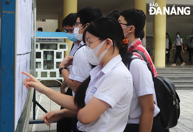 Các thí sinh tra cứu danh sách phòng thi tại điểm thi Trường THPT Trần Phú. Ảnh: NGỌC HÀ