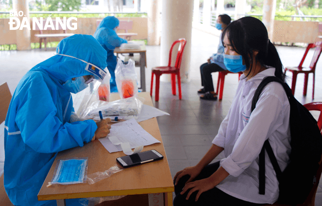 Lực lương y tế đang cập nhật thông tin của học sinh khi đến xét nghiệm Covid-19 tại Trường THPT chuyên Lê Quý Đôn, quận Sơn Trà. Ảnh: XUÂN DŨNG