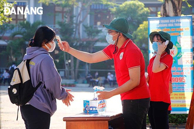 Các thi sinh được đo thân nhiệt, rửa tay sát khuẩn trước khi vào phòng thi. Ảnh: XUÂN DŨNG