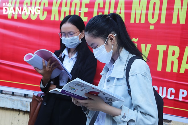 Thí sinh tranh thủ ôn lại bài trước khi vào điểm thi THCS Huỳnh Thúc Kháng. Ảnh: NGỌC HÀ.