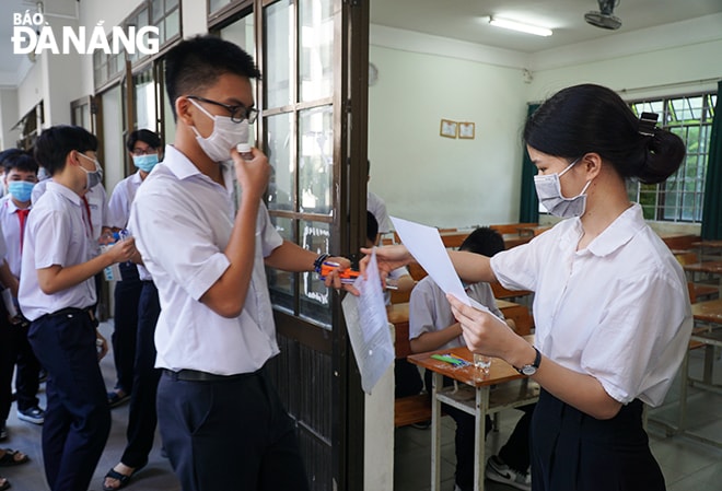 Cán bộ coi thi điểm danh thí sinh trước khi vào phòng thi tại điểm thi Trường THPT Phan Châu Trinh (quận Hải Châu). Ảnh: XUÂN DŨNG