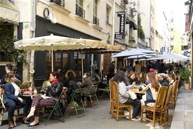 Người dân thưởng thức đồ uống bên ngoài một nhà hàng ở Paris, Pháp, ngày 19/5/2021. Ảnh: AFP/TTXVN