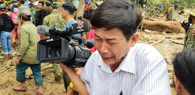 Phóng viên Đoàn Hữu Trung - TTXVN quay máy đi chỗ khác, bật khóc khi thi thể một em bé được đưa ra từ bùn đất ở Trà Leng, 2020. Ảnh: HOÀNG THẾ LỰC