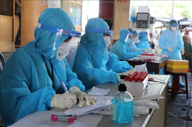 Cán bộ y tế lấy mẫu xét nghiệm để sàng lọc Covid-19. Ảnh: TTXVN
