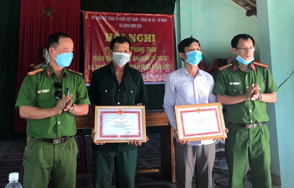 Công an xã Bình Định Bắc trao tặng giấy khen của Giám đốc Công an tỉnh cho 2 công dân Đặng Văn Thông và Lê Công Lợi. Ảnh C.R