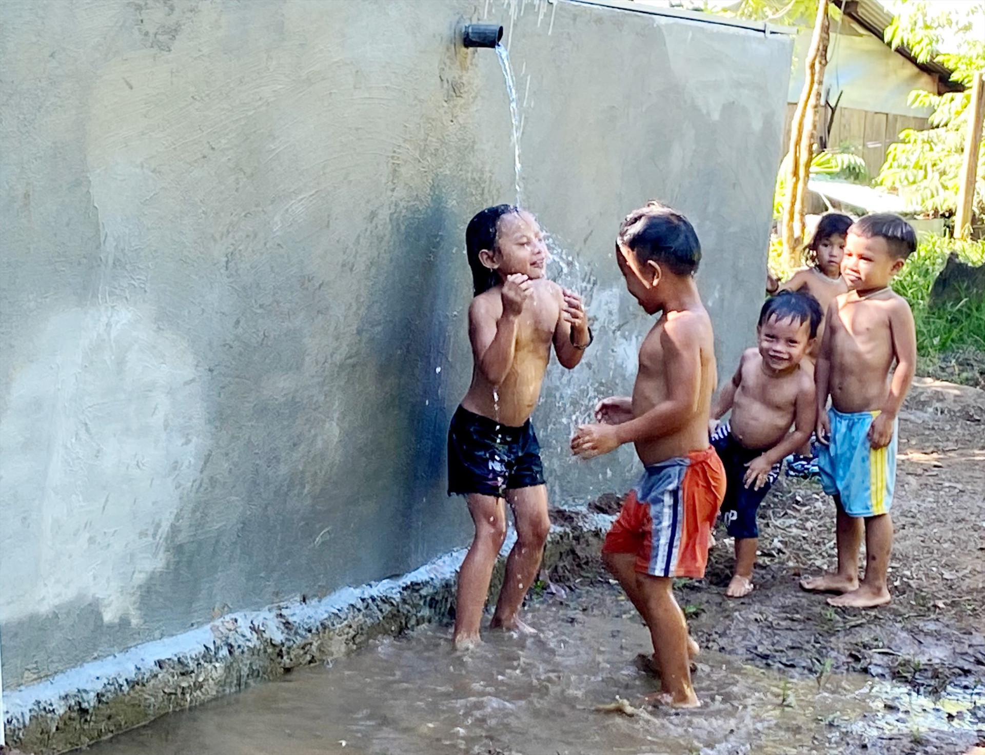 Trẻ con vui đùa bên công trình nước sạch vừa được trao tặng. Ảnh: T.Sỹ