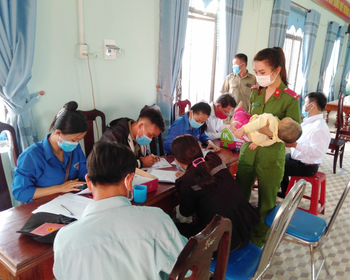 Thượng úy Đoàn Thị Hải Vân (Công an thị trấn Hương An) ẵm em bé giúp một bà mẹ làm thủ tục cấp căn cước công dân vào tháng 5 vừa qua.
