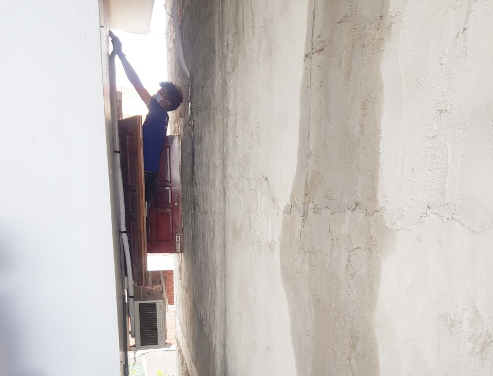 Luồn lách không gian chật hẹp giữa hai bức tường nhà để gắn đường dẫn ống nước máy lạnh. Ảnh: H.Q