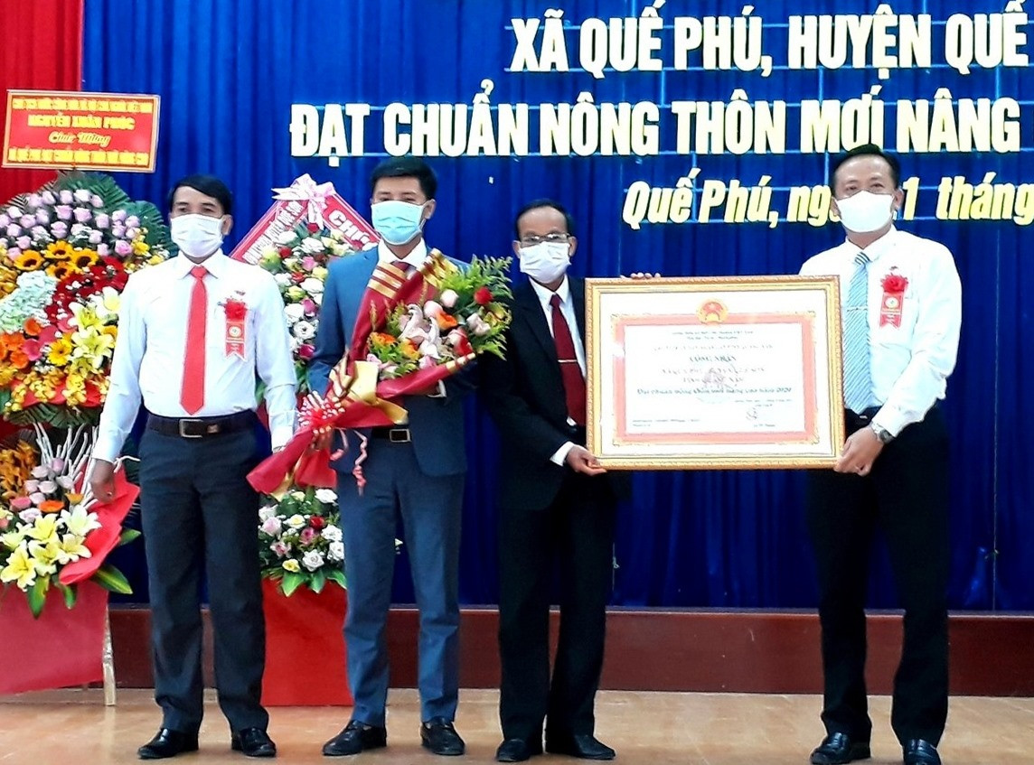 Thừa ủy quyền của UBND tỉnh, lãnh đạo huyện Quế Sơn trao bằng công nhận xã đạt chuẩn NTM nâng cao năm 2020 cho lãnh đạo xã Quế Phú vào sáng nay 21.7. Ảnh: N.S