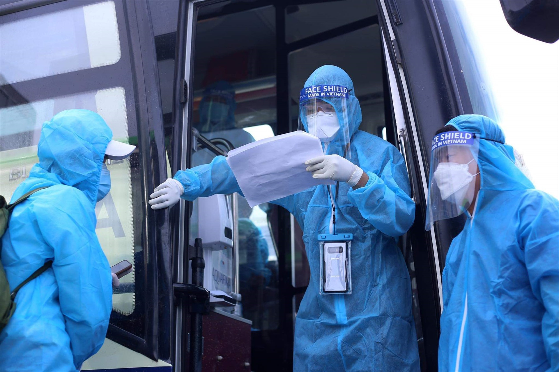 Anh Dương Quang Dũng và cán bộ y tế kiểm tra thông tin “hàng khách” trước khi lên xe.