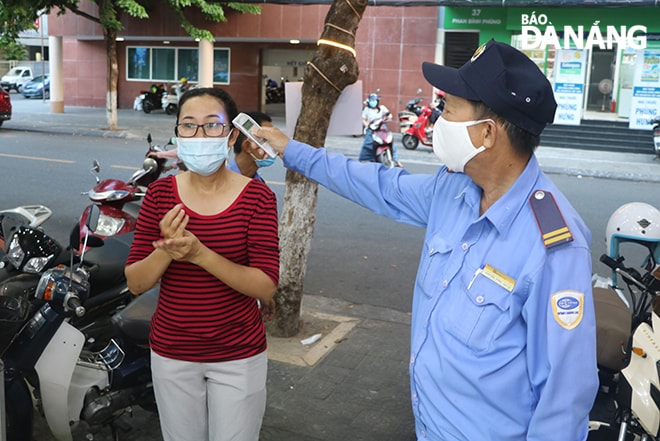 Nhân viên Danavi Mart đo thân nhiệt cho khách trước khi vào mua sắm. Ảnh: VĂN HOÀNG.