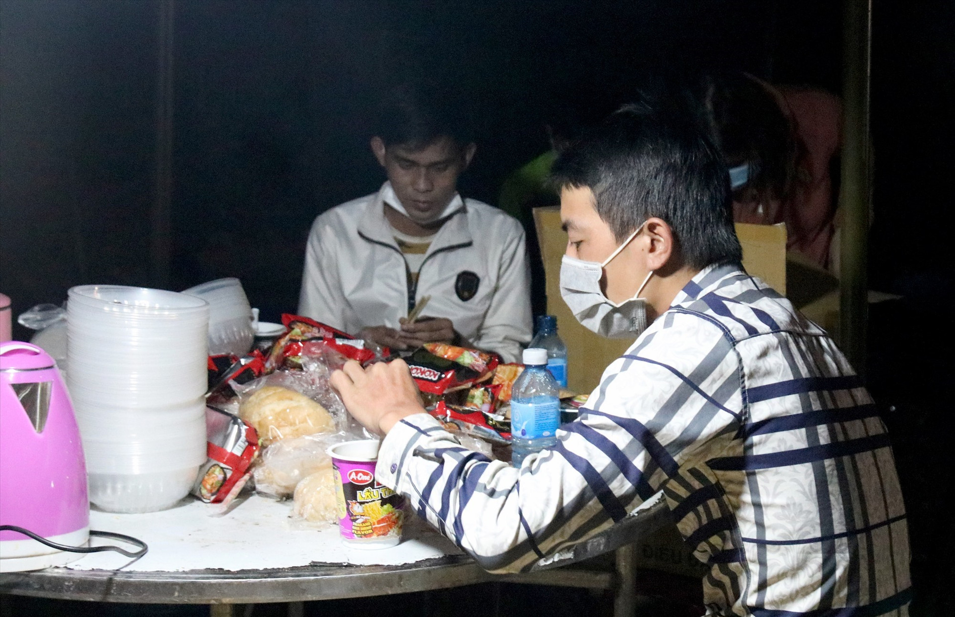 Người dân ăn vội mì gói, bánh mỳ để tiếp tục di chuyển qua địa bàn Quảng Nam trong đêm. Ảnh: H.Q