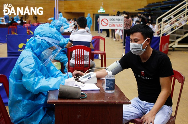 Nhân viên y tế khám sàng lọc trước khi tiêm cho người dân. Ảnh: XUÂN DŨNG