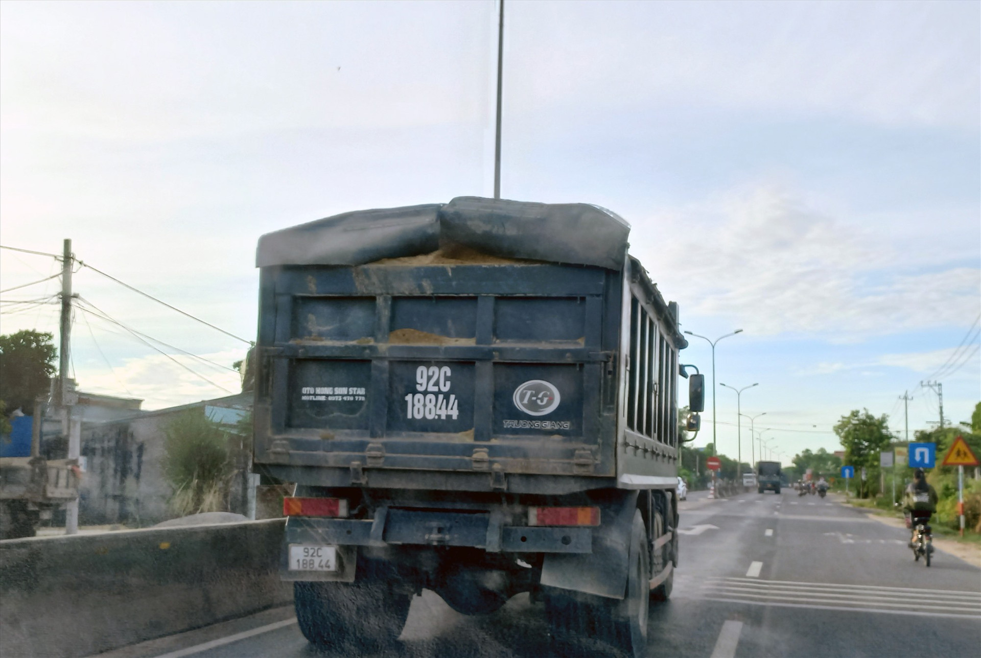 Xe tải chở quá kích thước thành, thùng hàng, để rơi vãi chạy trên quốc lộ 1 qua Thăng Bình. Ảnh: C.T