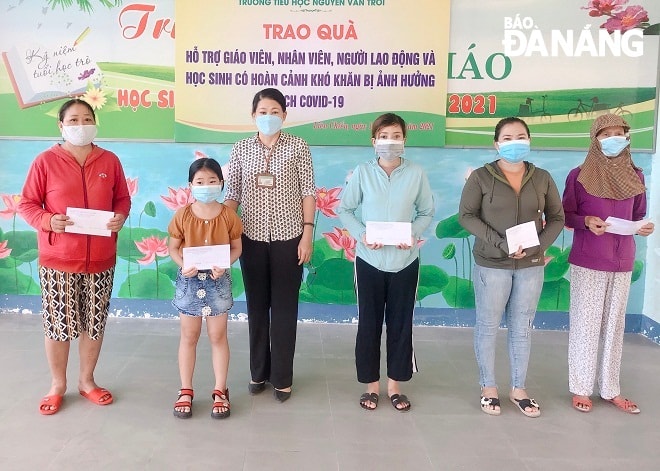 Ban giám hiệu Trường tiểu học Nguyễn Văn Trỗi trao quà hỗ trợ cho giáo viên, nhân viên và học sinh. Ảnh: NGỌC ĐOAN