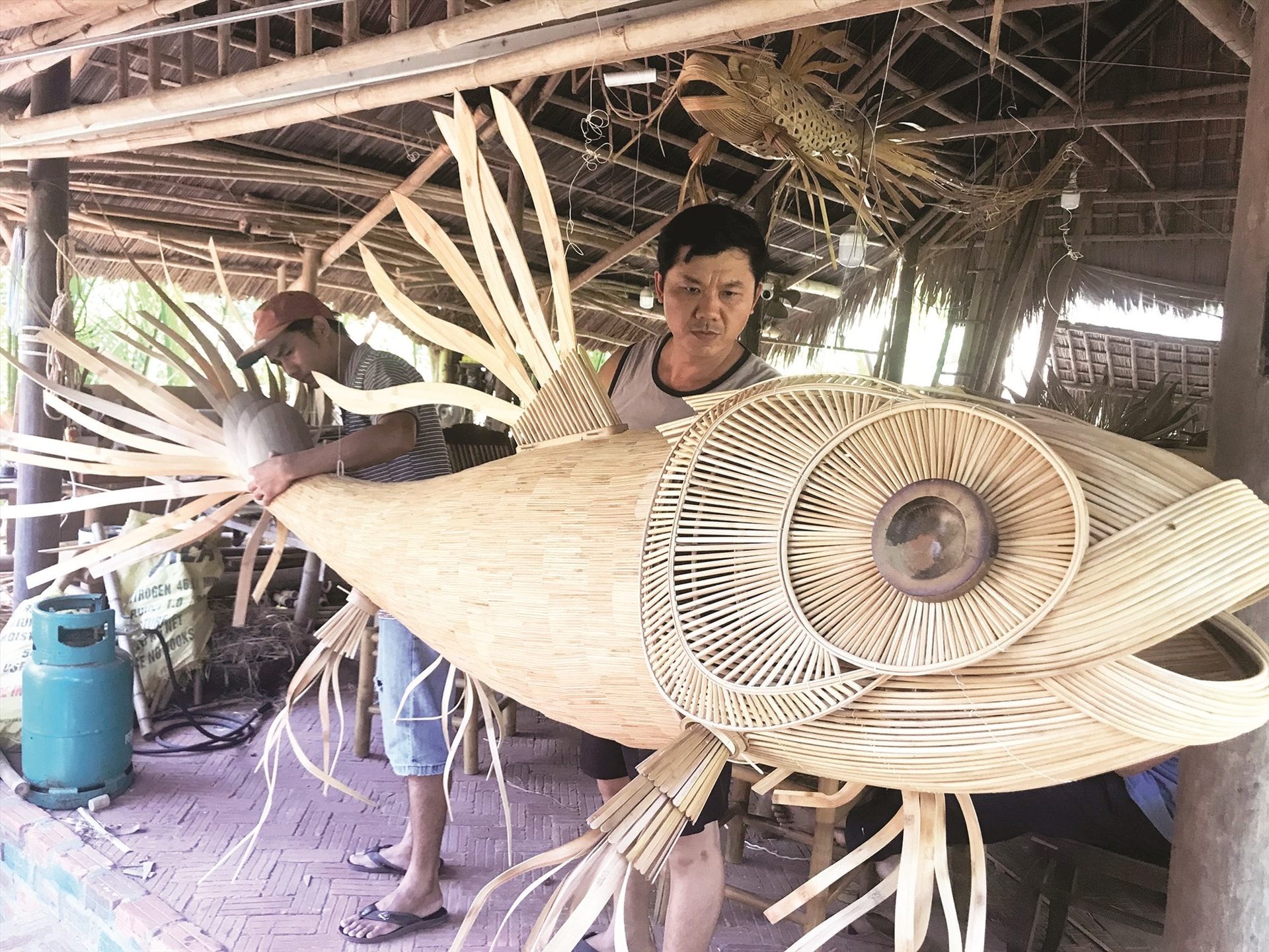 A Koi fish-shaped lantern is being completed by Mr. Tan (Right), the owner of Tâboo bamboo workshop and his skilled workers. This workshop attracted many foreign tourists before the Covid-19 epidemic.