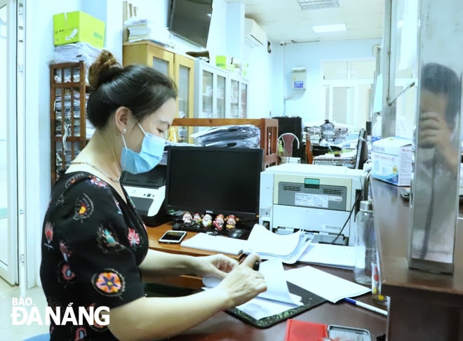 Cán bộ bộ phận Một cửa phường Hòa An đóng dấu để cấp giấy đi đường cho các trường hợp cấp thiết. Ảnh: NGỌC PHÚ
