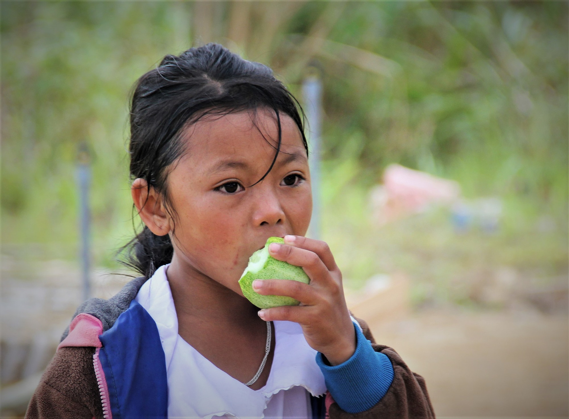 Một học sinh ở xã biên giới Ch’Ơm tranh thủ lót dạ bằng quả dưa trên đường đến lớp.