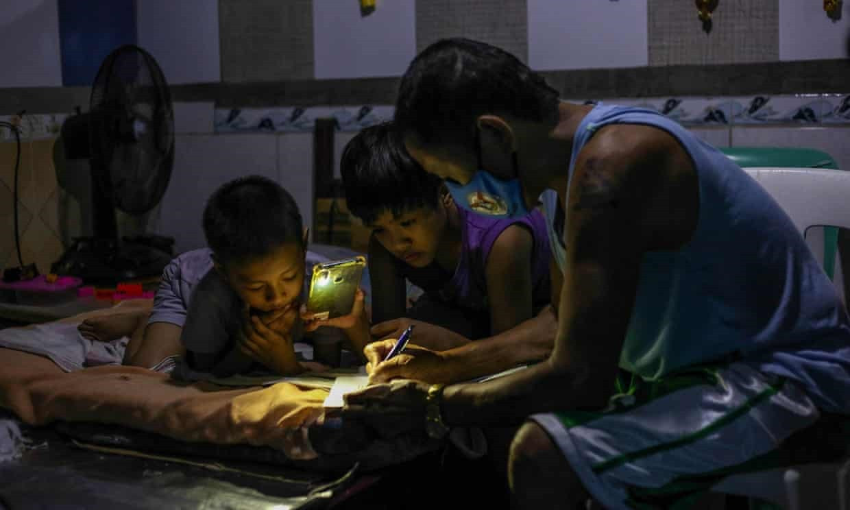 Petronilo Pacayra ( Quezon, Philippines) hướng dẫn cho các con học trực tuyến trong căn phòng chật chội và thiếu ánh sáng. Ảnh: Getty Images