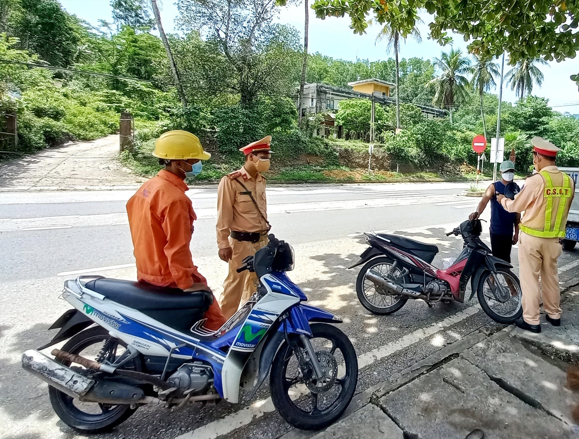 Một công nhân đội mũ bảo hộ lao động điều khiển xe máy bị lực lượng chức năng tuýt còi. Ảnh: S.C