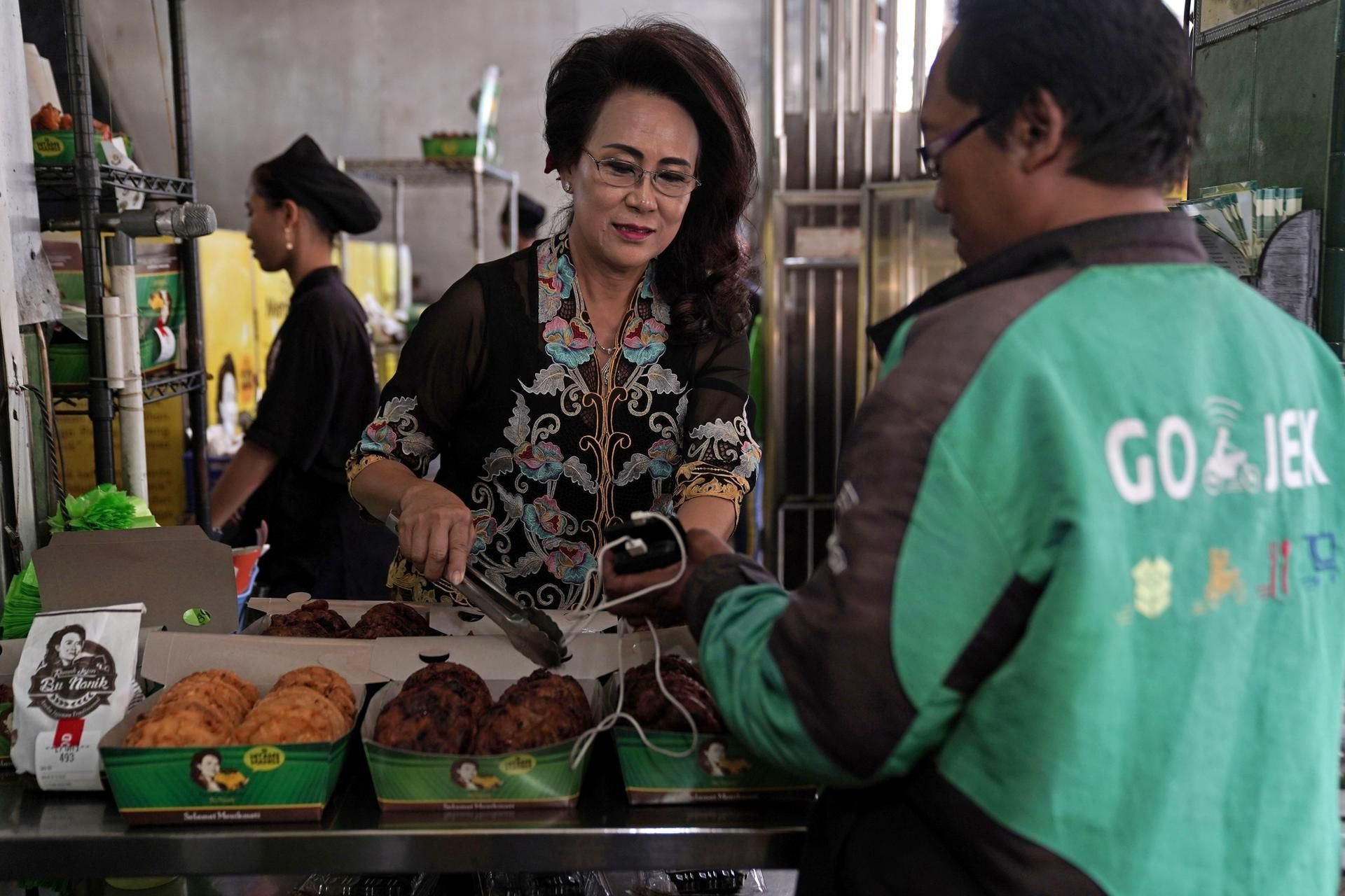 Tài xế công nghệ nhận đơn hàng tại quầy thực phẩm ở Jakarta, Indonesia. Ảnh: Bloomberg