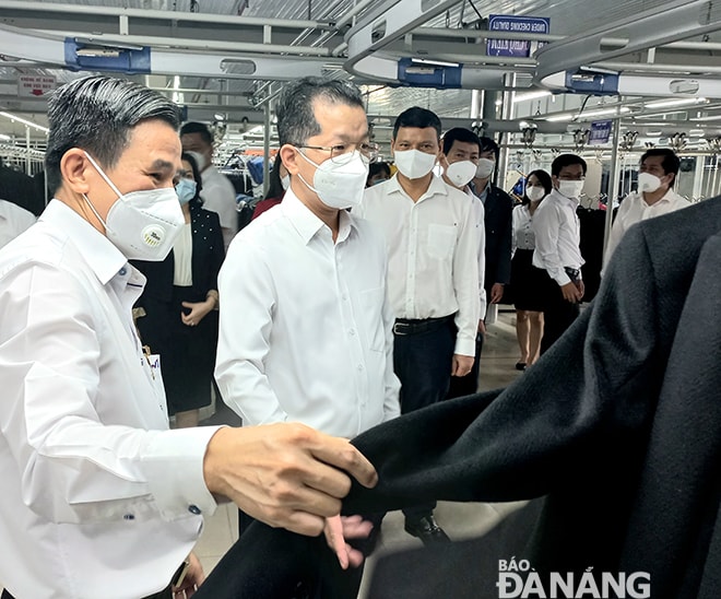 Bí thư Thành ủy Nguyễn Văn Quảng (giữa) được lãnh đạo Tổng Công ty CP Dệt may Hòa Thọ giới thiệu sản phẩm xuất khẩu của doanh nghiệp. Ảnh: TRIỆU TÙNG