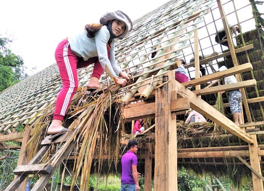 Bí thư Chi bộ thôn 1 (xã Trà Cang, Nam Trà My) - Trương Thị Luôn cùng người dân tham gia lợp nhà truyền thống. Ảnh: ALĂNG NGƯỚC