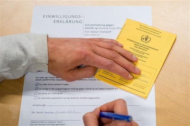 Người dân điền thông tin vào bản khai bên thẻ Chứng nhận tiêm vaccine ngừa COVID-19 do Tổ chức Y tế Thế giới (WHO) cấp phép, tại điểm tiêm chủng ở Halle/Saale, miền Đông Đức.