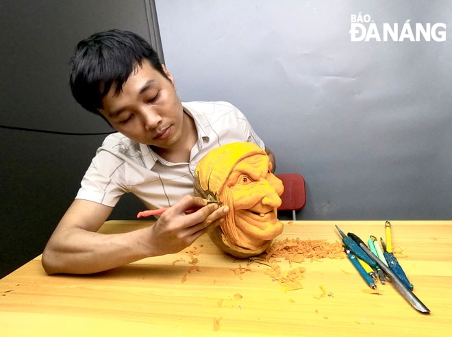 Anh Nguyễn Anh Vũ khắc mặt nạ quỷ từ quả bí ngô phục vụ trang trí lễ Halloween. Ảnh: THANH TÌNH