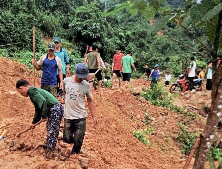 Người dân thôn 2 (xã Trà Ka) dọn dẹp đất đá bị sạt lở gây ách tắc giao thông sau đợt mưa lớn từ ngày 22 - 24.10.2021. Ảnh: TRÀ MY